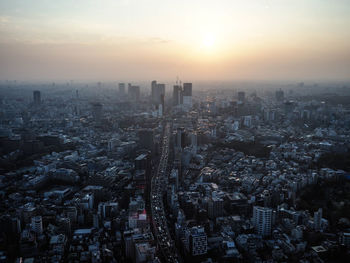 High angle view of illuminated city buildings against sky during sunset