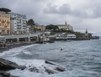 Buildings by sea against sky in city