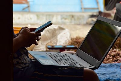 Midsection of man using laptop at table