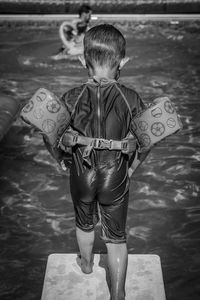 Rear view of wet boy standing on diving platform