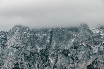 Layer of clouds covering rocky mountain peaks at vrsic mountain pass in julian alps in slovenia