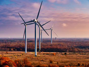 Wind turbines on field against sky