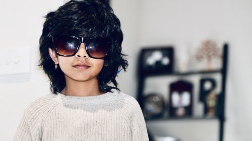 Portrait of young woman wearing sunglasses while standing at home