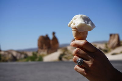 Close-up of hand holding ice cream against sky