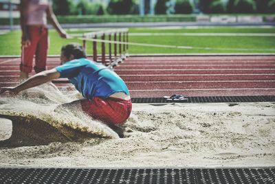 Side view of male long jumper on sand