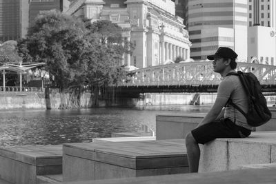 Young woman sitting by fountain in city