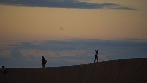 Rear view of man standing on mountain against sky during sunset