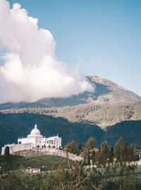 Buildings on mountain against cloudy sky