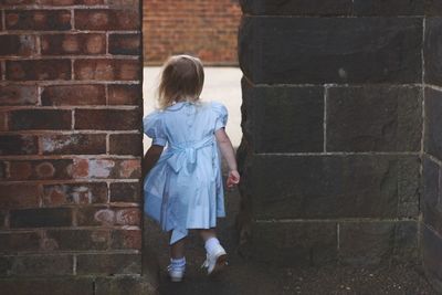 Rear view of girl walking by walls