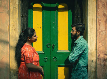 Side view of young woman standing against wall