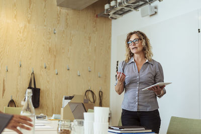 Confident mature businesswoman with digital tablet discussing in meeting