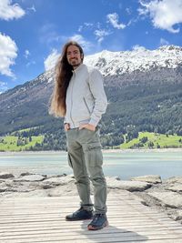 A young long-haired man posing in front of the lago di resia.