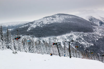 People on snow covered mountain against sky