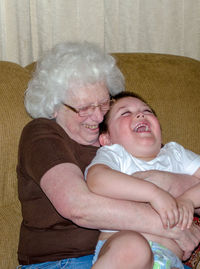 Grandmother hugs and tickles her 3 year old grandson 