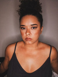 Portrait of young woman against wall at home