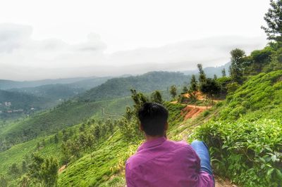 Rear view of man looking at mountains against sky