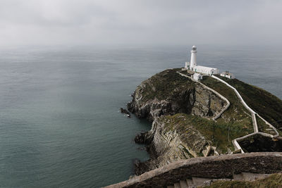 Lighthouse by sea against sky