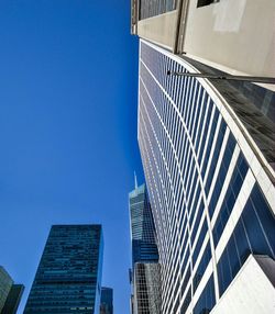 Low angle view of bank of america tower and skyscrapers against clear blue sky