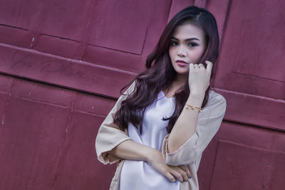 Portrait of beautiful young woman standing against wall