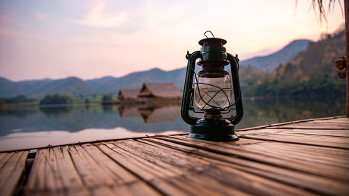 Lighting equipment on pier at lake against sky during sunset