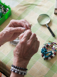 High angle view of woman making bracelet on table