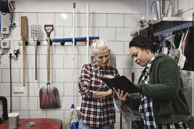 Female workers discussing over digital tablet while working in brewery