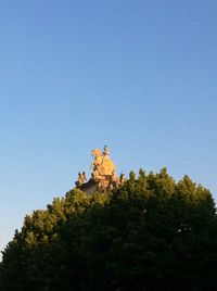 Low angle view of trees against clear blue sky