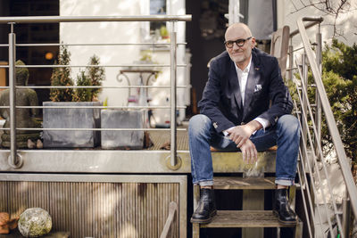 Senior man sitting on stairs of his patio