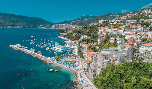 High angle view of buildings and sea against blue sky