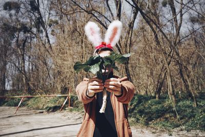 Young man wearing bunny ear headband at forest