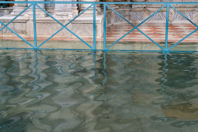 Reflection of metal fence on swimming pool