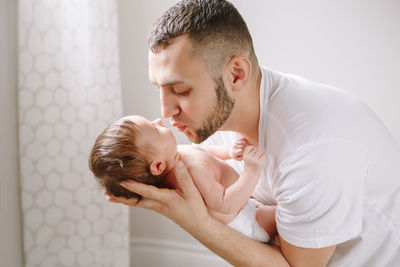 Happy young caucasian father kissing newborn baby. dad man parent holding rocking child daughter 