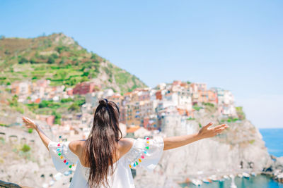 Rear view of woman with arms raised against sky