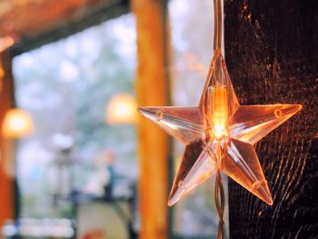 Close-up of illuminated star shape decoration hanging against window