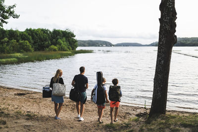 Rear view of family walking towards beach during weekend
