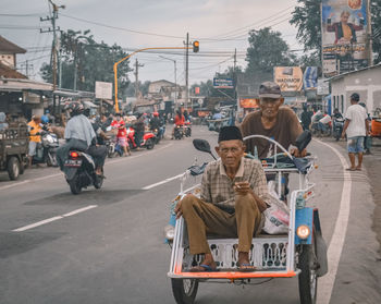 People riding motorcycle on road in city