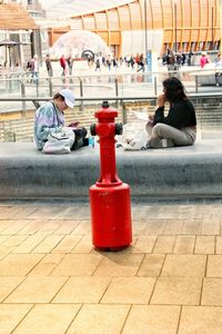 Side view of people sitting on footpath