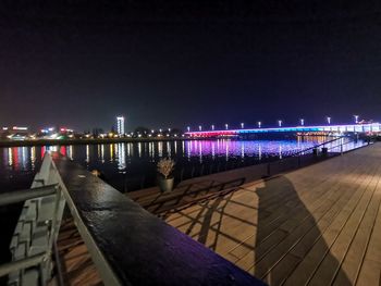 Illuminated bridge over river against sky at night