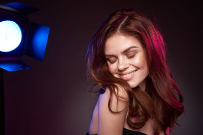 Portrait of young woman looking away against black background