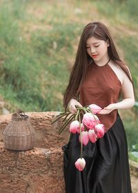 Young woman with pink flower against blurred background