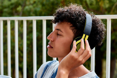 Young man with afro hair closes his eyes while listening to music