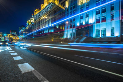 Light trails on city street by buildings at night