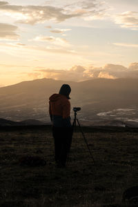 Rear view of man photographing at sunset 