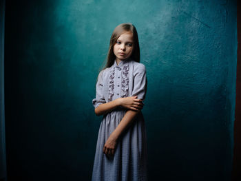 Portrait of girl standing against blue background