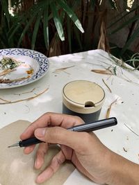 Midsection of person holding coffee cup on table