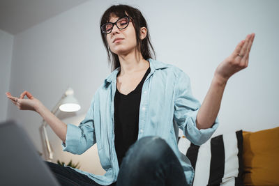 Frustrated young woman gesturing by laptop in office