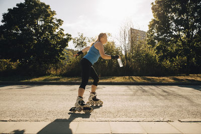Female athlete roller skating on street during sunny day