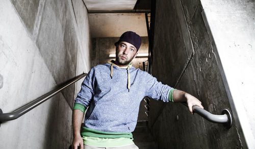 Portrait of young man standing against wall