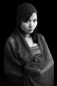 Close-up portrait of young woman against black background