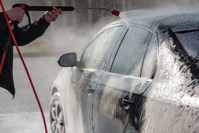 Cropped image of man washing car at garage